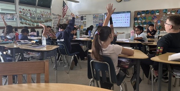 Students in a classroom with hands raised and active participation